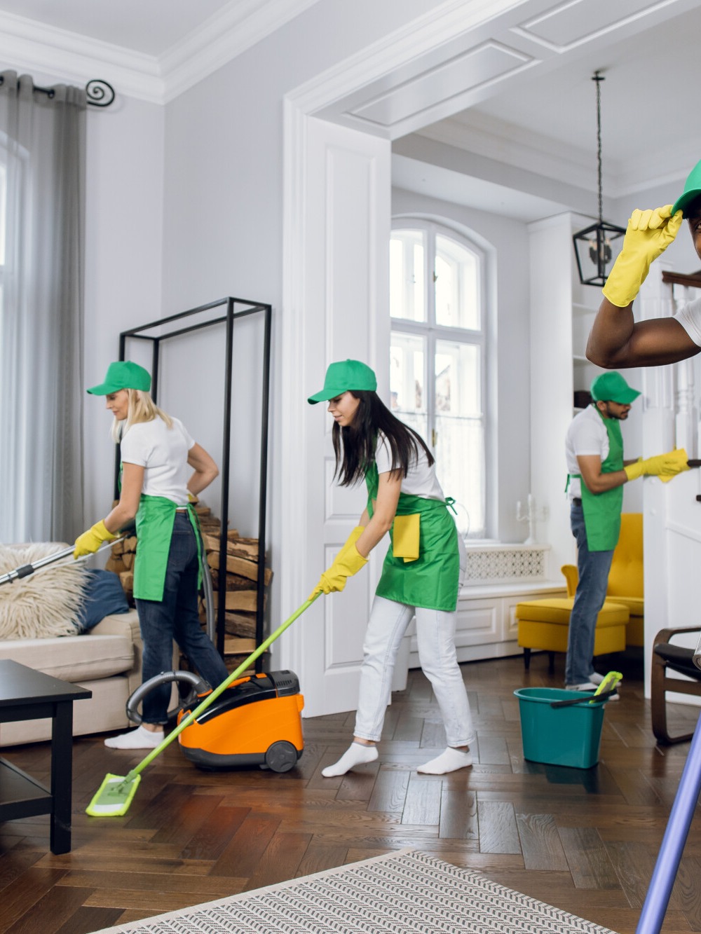 Two members of the cleaning team mopping and vacuuming a client's living room