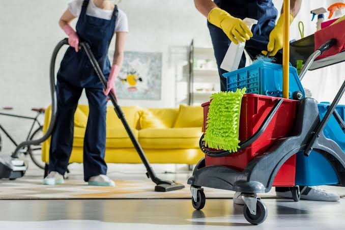 A fully stocked cleaning cart with mop, bucket, and supplies
